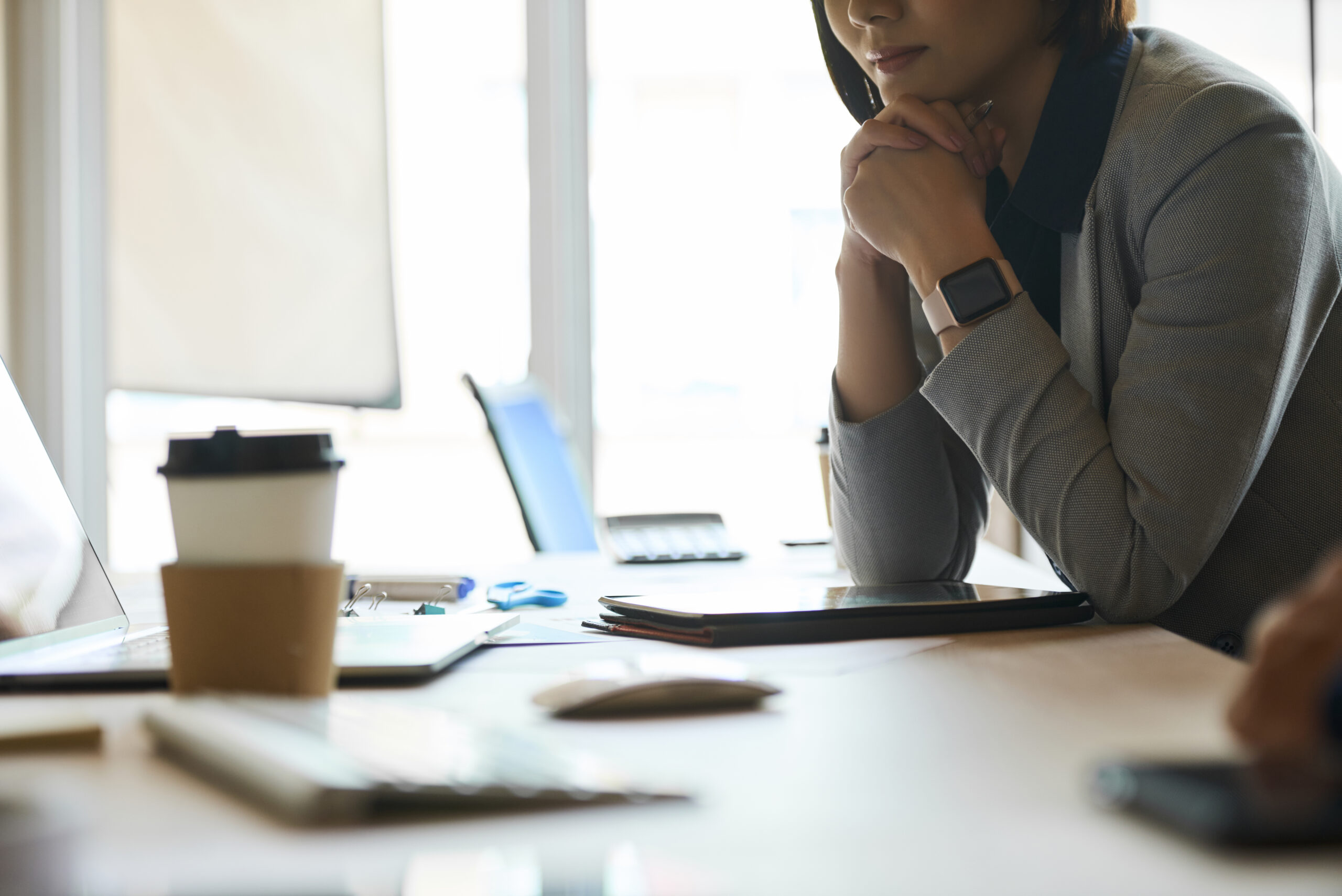 Cropped image of pensive elegant businesswoman sitting at office desk and reading information on laptop screen